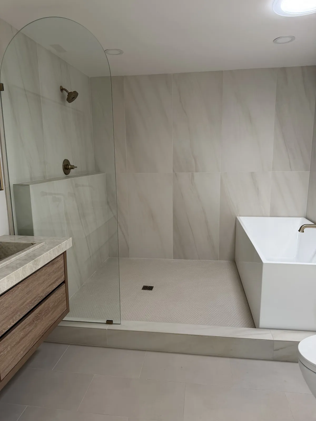 Custom residence bathroom with curbless walk-in shower, frameless glass panel and freestanding tub in Southern California