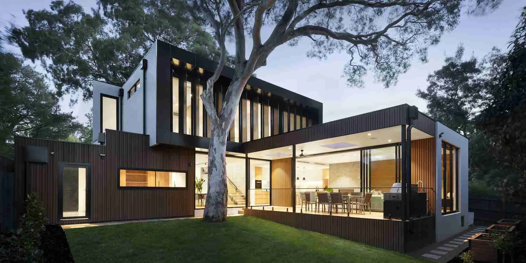 Luxury Southern California residence at dusk with glass walls opening onto a garden